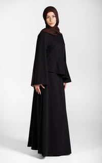 Woman wearing a modest black skirt and top set with a brown hijab on a white background