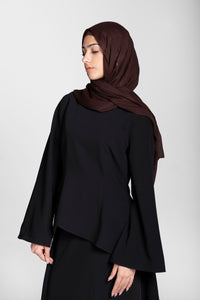 Woman wearing a modest black skirt and top set with a brown hijab on a white background