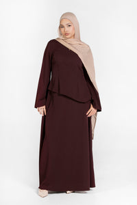 Woman wearing a brown dress and beige hijab on a white background