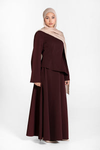 Woman wearing a brown skirt and top set and beige hijab on a white background