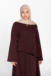 Woman wearing a brown modest outfit with a beige hijab on a white background