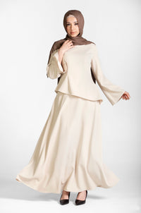 Woman wearing a beige/cream top and skirt coord set with a brown hijab on a white background