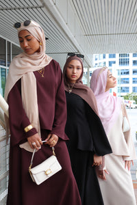 Women wearing modest black/beige/maroon skirt and top set with hijabs in an outside setting