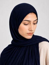 Woman wearing a dark navy blue jersey hijab against a white background